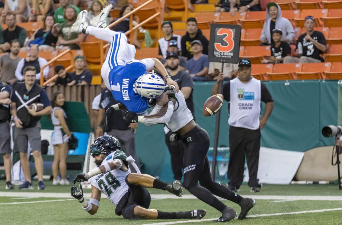 BYU quarterback Zack Wilson fumbles the ball after he's hit by Hawaii defensive backs Donovan Dalton (29) and Eugene Ford during the Hawaii Bowl on Dec. 24, 2019, in Honolulu.