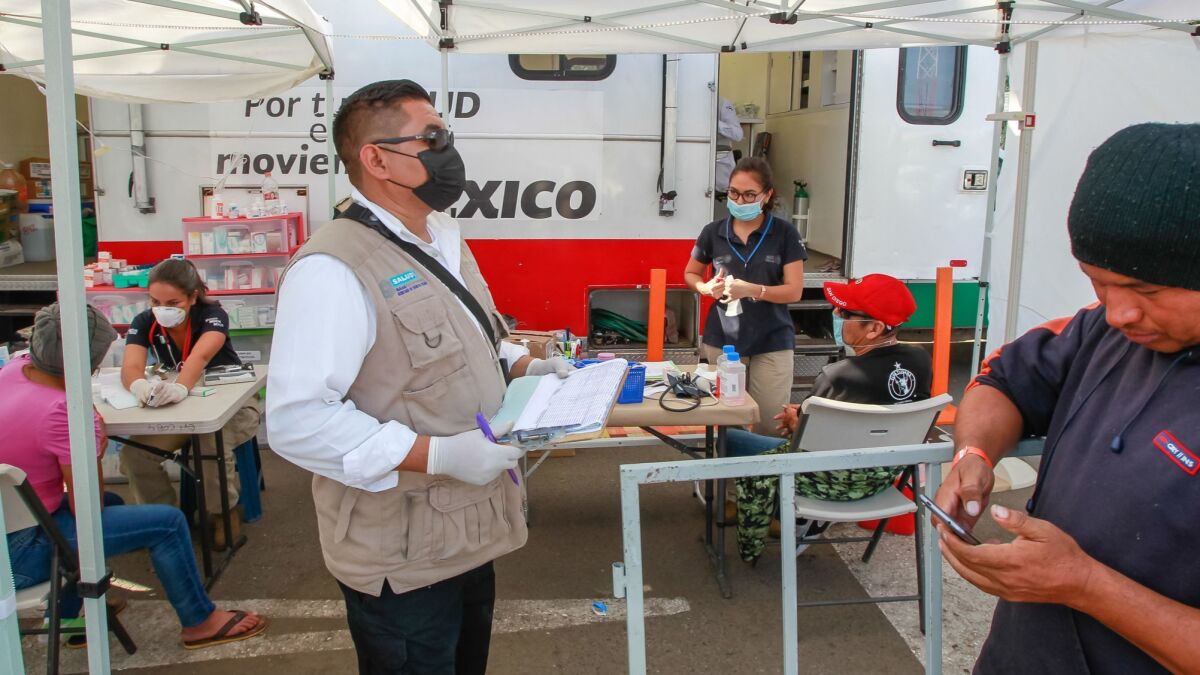 Workers from a Mexican government organization called Secretaria de Salud del Estado offer health services outside the temporary caravan migrant shelter called Unidad Deportiva Benito Juarez on Wednesday in Tijuana, Mexico.