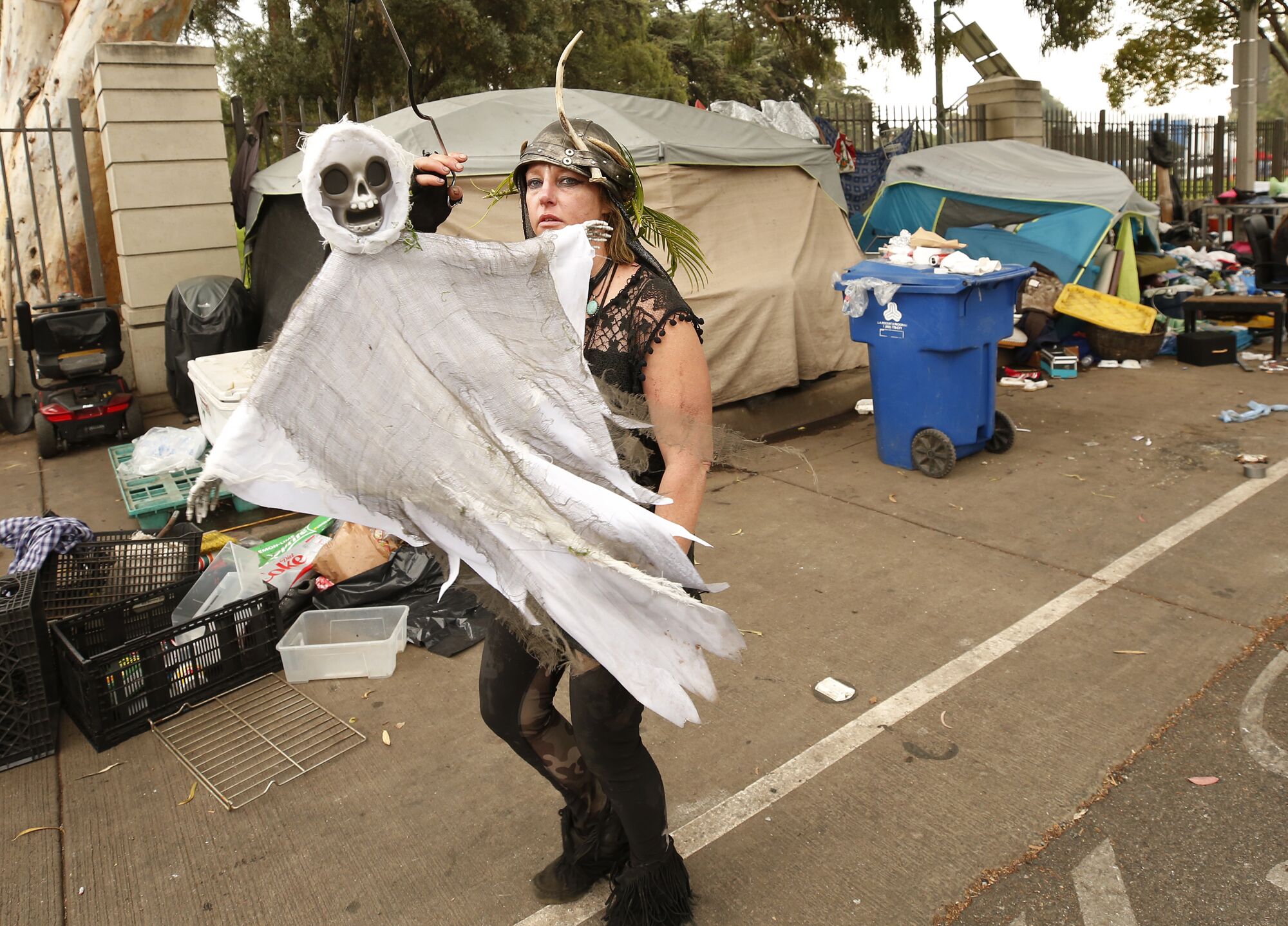 A woman in a helmet carried a Halloween decoration with a skeleton face and cloth body