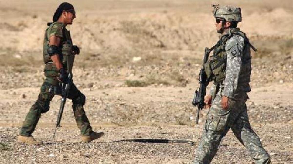 JOINING FORCES: A member, left, of one of Iraq's Concerned Local Citizen (CLC) groups, U.S. sanctioned neighbourhood watch groups, walks past an American soldier with the 101st Airborne Division during a joint operation.