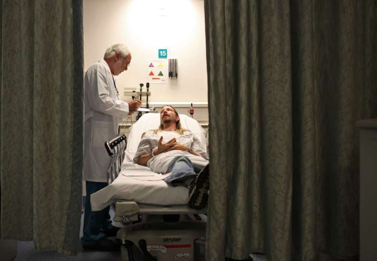 Emergency-room doctor Philip Schwarzman, left, examines patient John O'Brien at Providence St. Joseph Medical Center in Burbank.