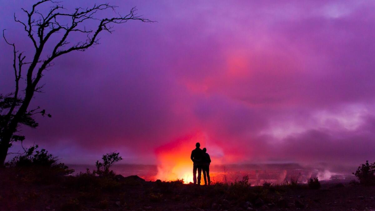 An eruption of molten lava is witnessed by two visitors to Hawaii Volcanoes National Park on the Big Island of Hawaii.