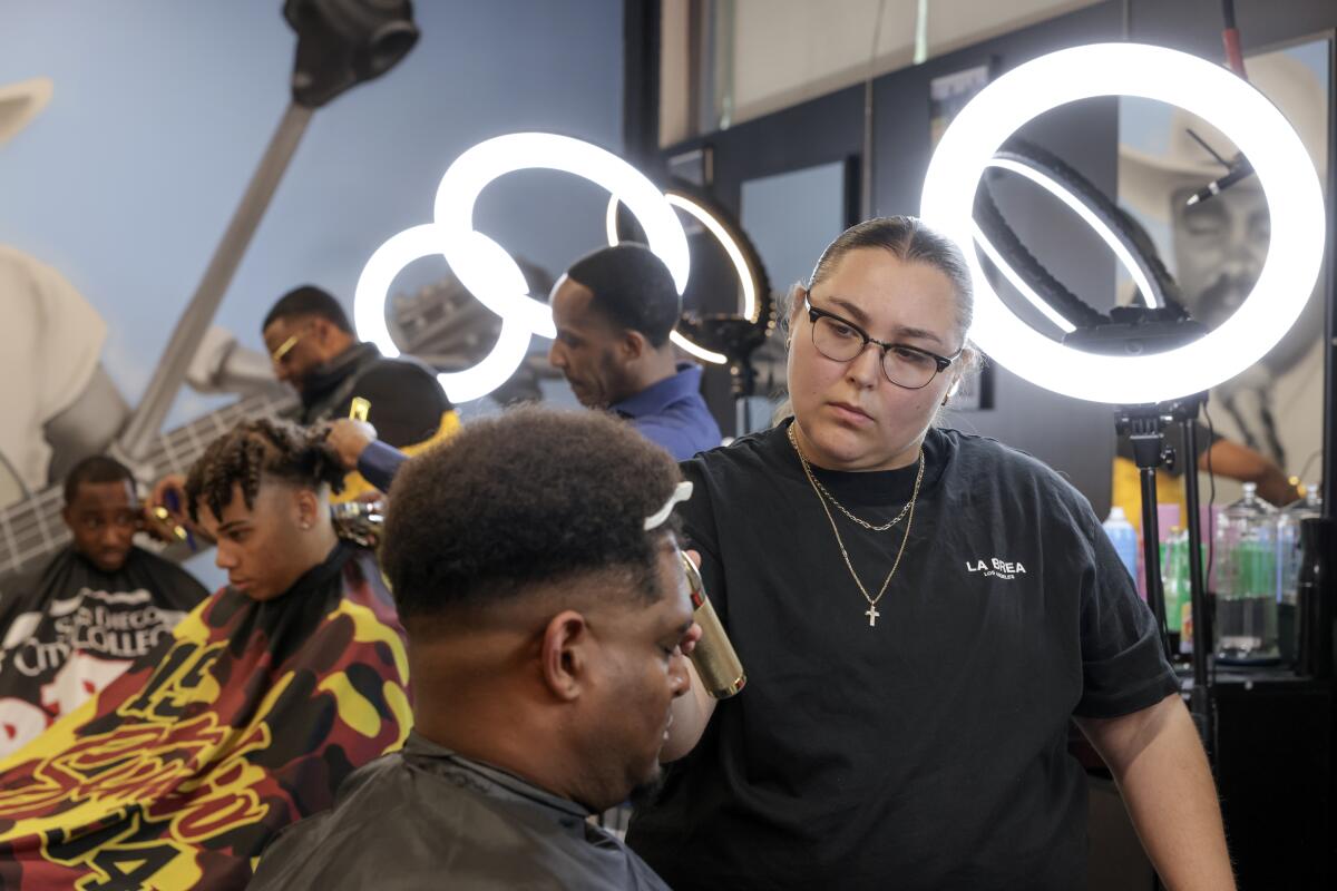 Barber Franny Vaughan cuts the hair of Hector Colon during the grand opening of Fresh Cutz.