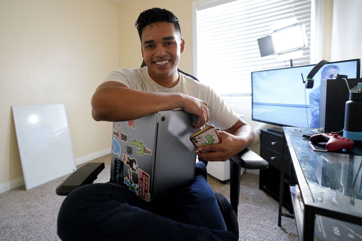 Jesus Morales sitting in an office holding his computer and phone