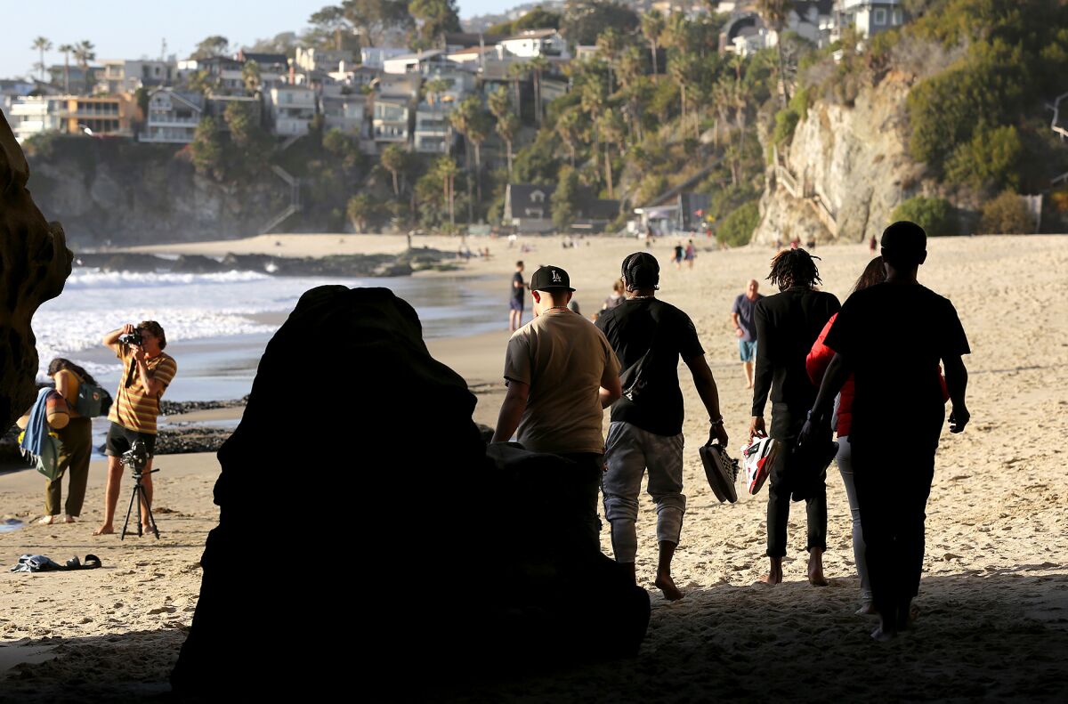Beach-goers walk the sands at Thousand Steps beach in Laguna Beach in April this year.