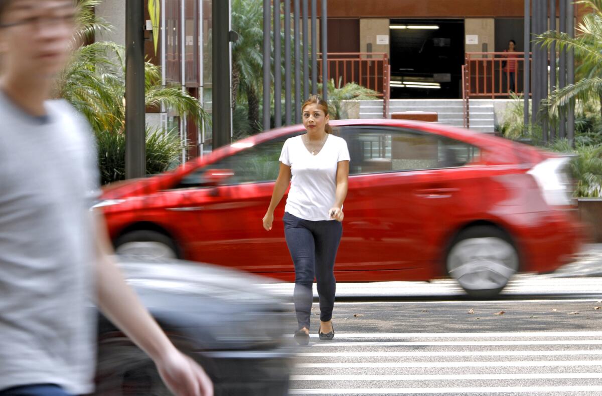 A pedestrian is seen between two vehicles as she crosses the street on the 500 block of N. Brand Blvd. in Glendale on Tuesday, July 29, 2014. The driver in the car in front of the pedestrian was pulled over by Glendale police for not yielding.