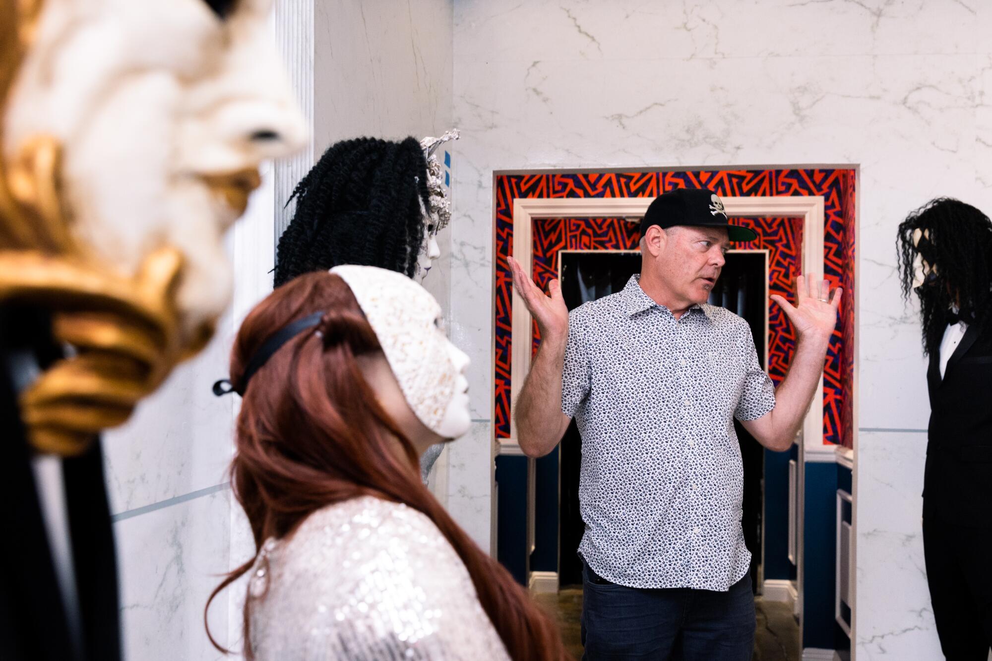 A man in a doorway surrounded by three masked figures.