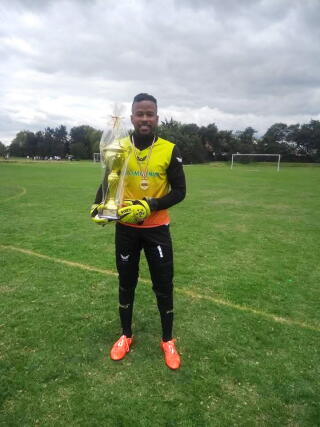 Soccer goalie Jerce Egbunik Reyes Barrios standing on the pitch with a trophy