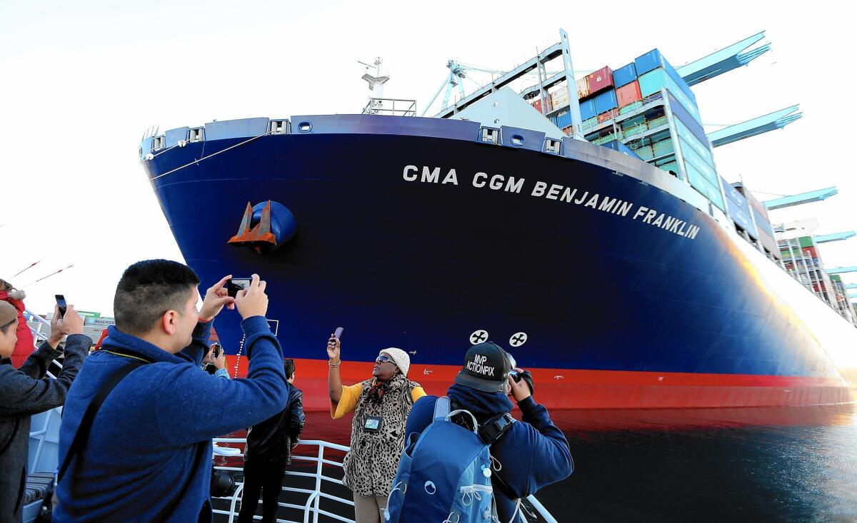 People aboard a passing boat take pictures of the CMA CGM Benjamin Franklin as it unloads cargo at the Port of Los Angeles. The Franklin is the largest container ship to visit a North American port.