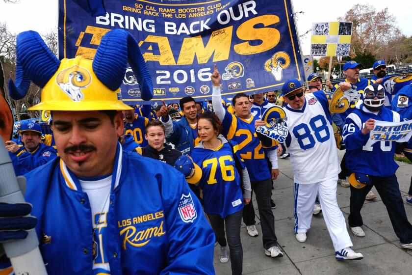 Rams football fans hold banners, wave signs and chant while marching around the L.A. Memorial Coliseum in January.