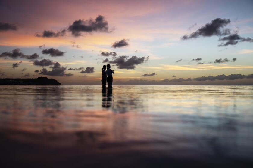 En esta imagen de archivo, dos turistas observan la puesta de sol en una popular playa en Tamuning, Guam, el 6 de mayo de 2019. (AP Foto/David Goldman, archivo)