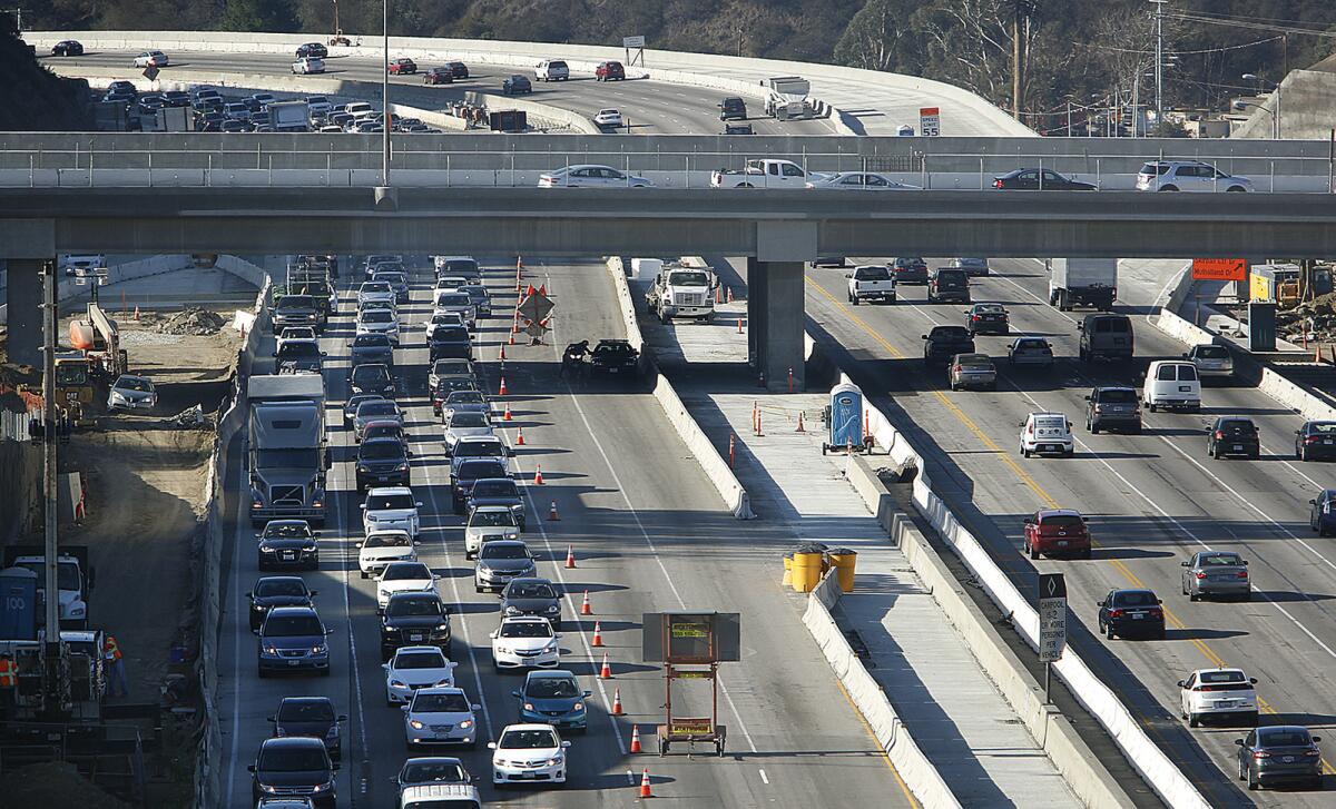 Motorists travel during rush hour on a section of the northbound 405 Freeway where workers had placed cones to close two lanes in preparation for paving work.