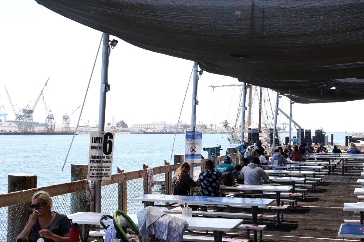 People eat at tables on the dock at the San Pedro Fish Market