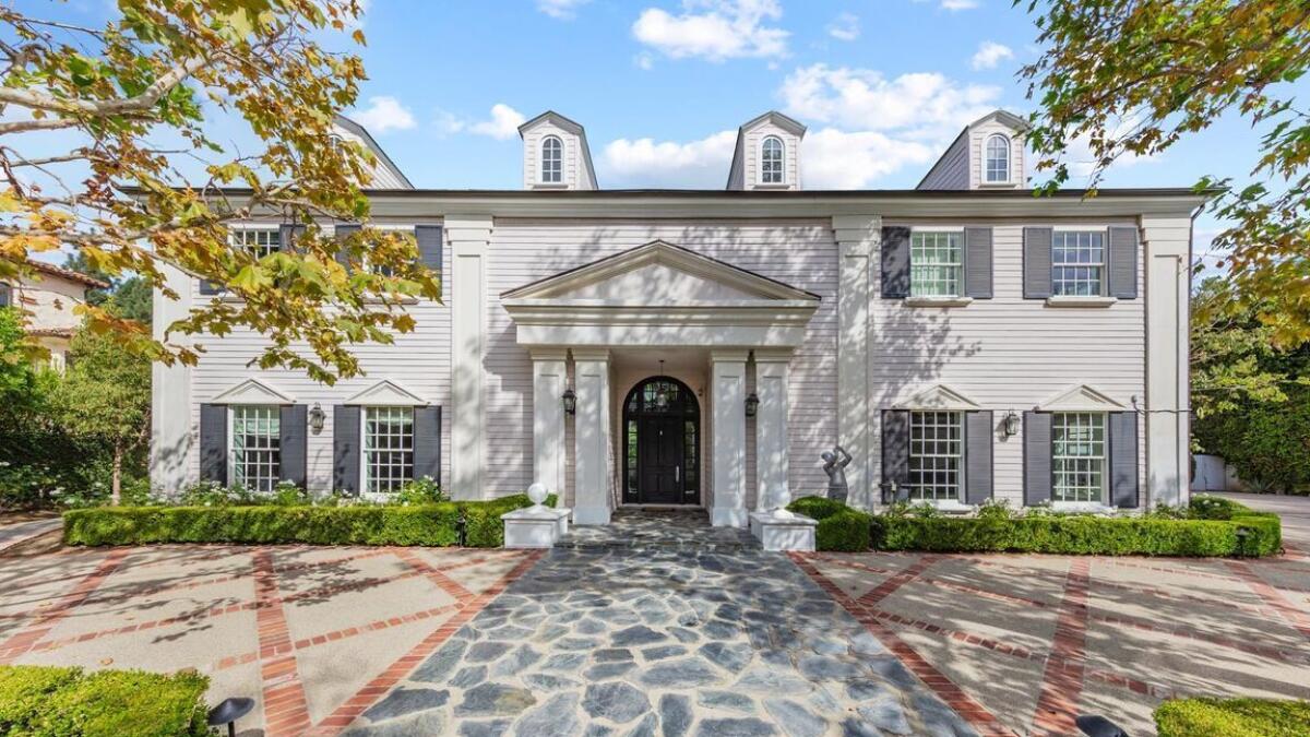 A white multilevel home with an arched doorway.