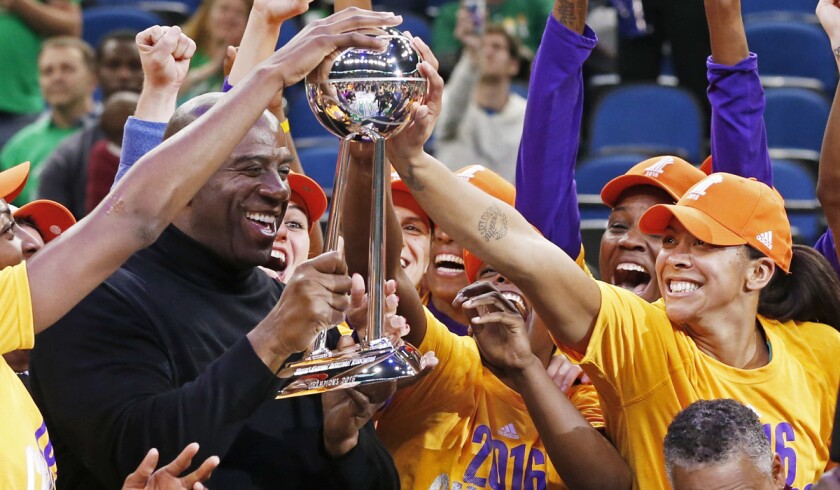 Sparks' Candace Parker, right, touches the trophy held by team owner Magic Johnson after the Sparks won the WNBA championship title over the Minnesota Lynx Thursday.