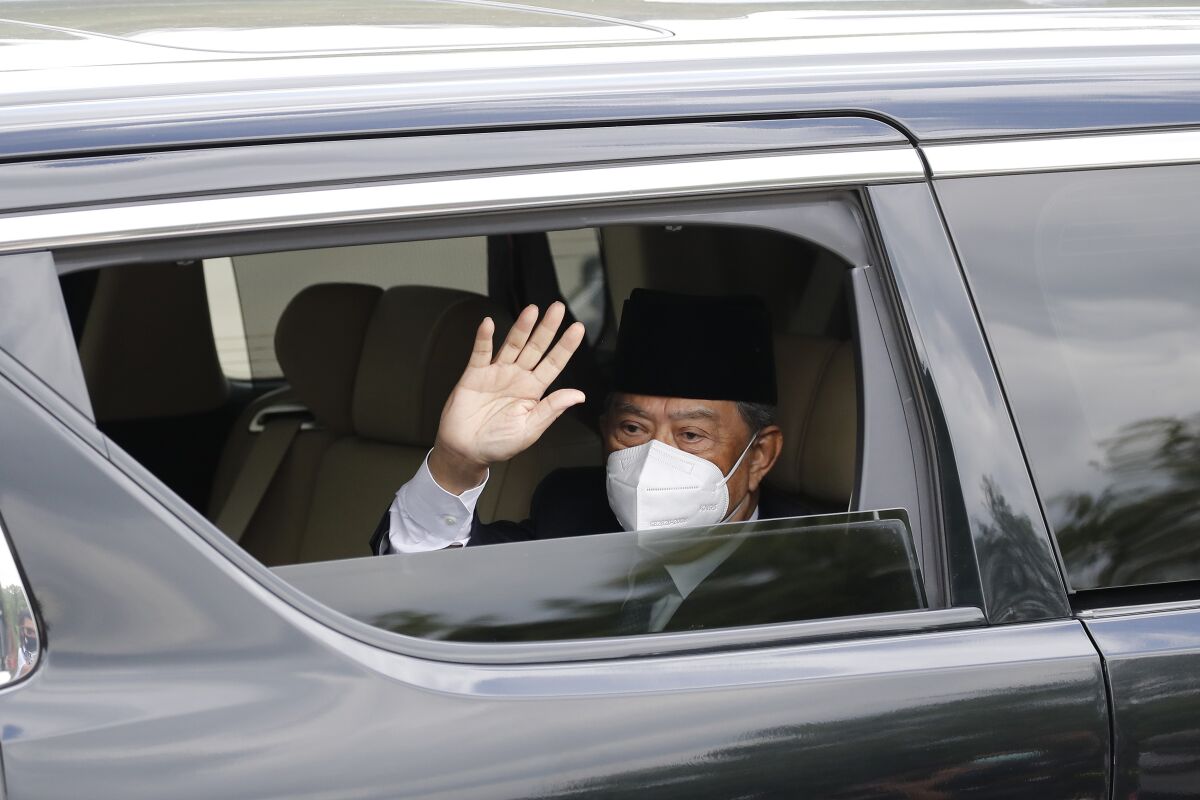 Embattled Malaysian Prime Minister Muhyiddin Yassin waves from a car while entering the National Palace to meet with the King in Kuala Lumpur, Malaysia, Monday, Aug. 16, 2021. Muhyiddin arrived at the palace for a meeting with the king Monday, where he is expected to hand in his resignation after conceding he didn't have majority support to rule. (AP Photo/FL Wong)