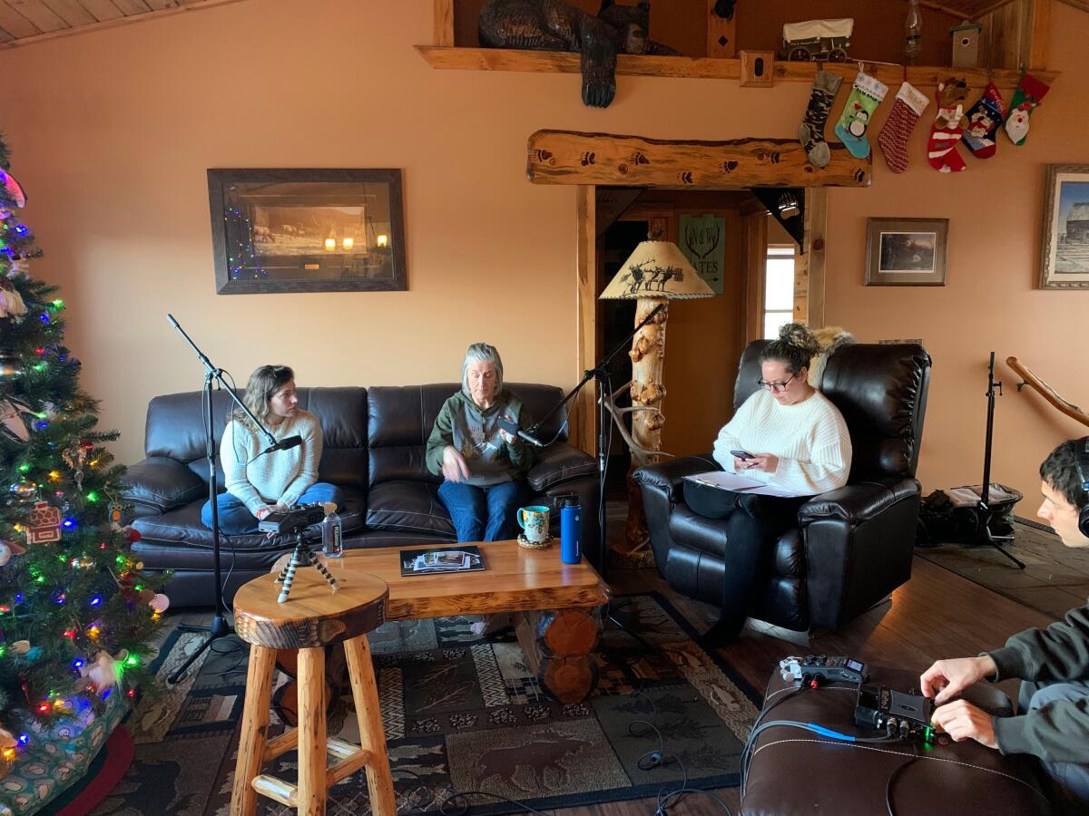 Four people sit in a living room decorated for Christmas.
