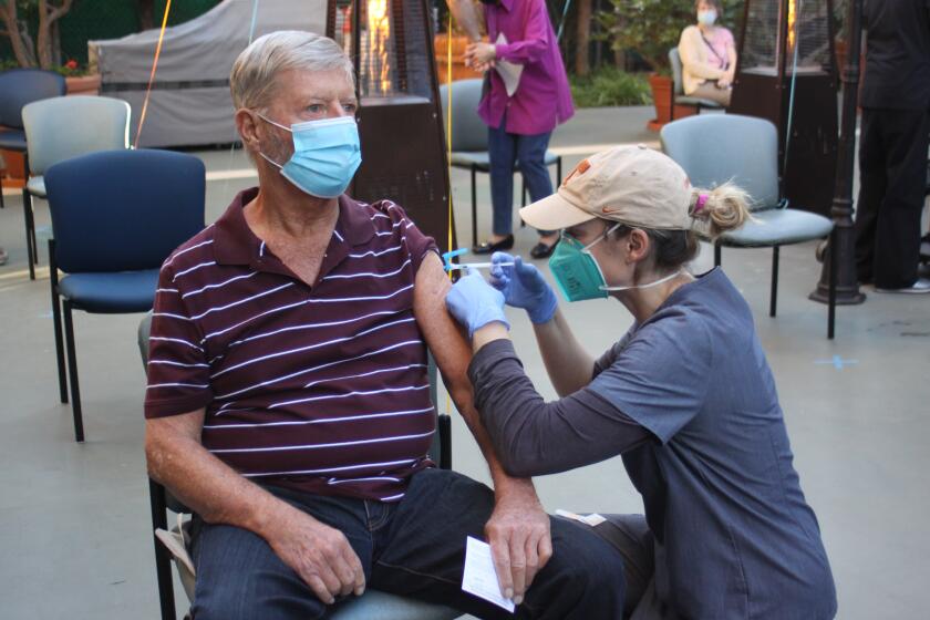 Chateau La Jolla resident Butch Hansen receives the first does of the COVID-19 vaccine.