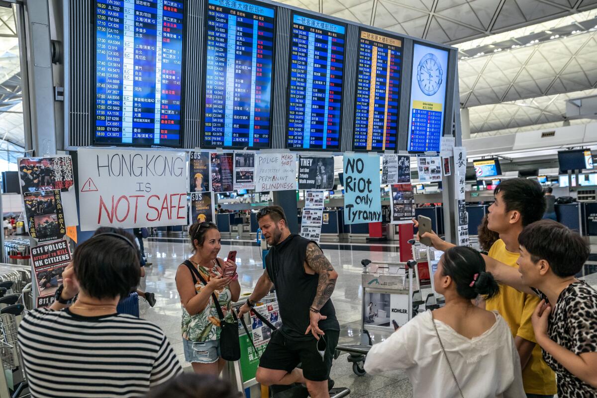 Tourists look at the information panel at the Hong Kong International Airport during a demonstration.