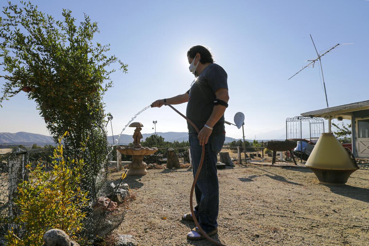 Zenón Mayorga waters a pomegranate tree at his home in Juniper Hills.