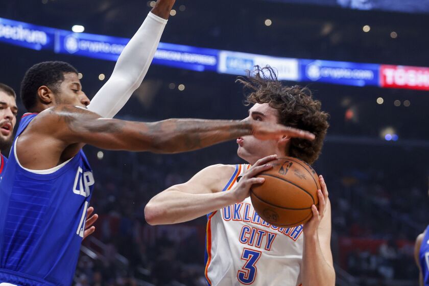 Oklahoma City Thunder guard Josh Giddey, right, is defended by Los Angeles Clippers forward Paul George during the first half of an NBA basketball game Tuesday, March 21, 2023, in Los Angeles. (AP Photo/Ringo H.W. Chiu)