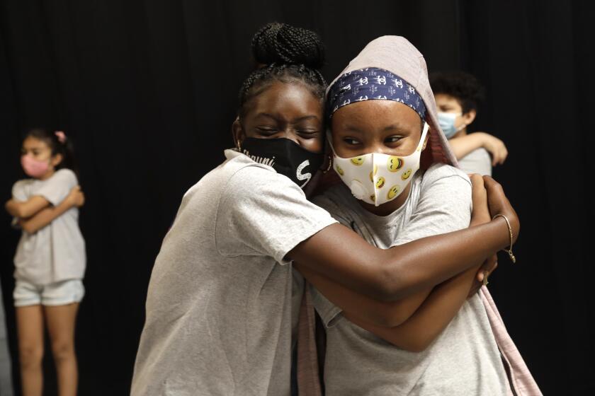 SOUTH LOS ANGELES, CA - JULY 15, 2021 - - Shauni Edmund, 13, left, and Ty'lir Langston, 11, hug during a mindfulness exercise before learning practical skills in technology at a tech summer camp at SoLA Impact's new Tech and Entrepreneurship CenterThe Beehive in South Los Angeles on July 15, 2021. Children learn animation, digital storytelling, video game design, Photoshop, coding and website design at the tech summer camp. The tech summer camp has been held over the last month, impacting about 100 local youth. Mayor Eric Garcetti visited The Beehive with other dignitaries and philanthropists. The event aims to highlight the practical ways that private, public and institutional capital can positively impact minority communities in South and East Los Angeles. (Genaro Molina / Los Angeles Times)