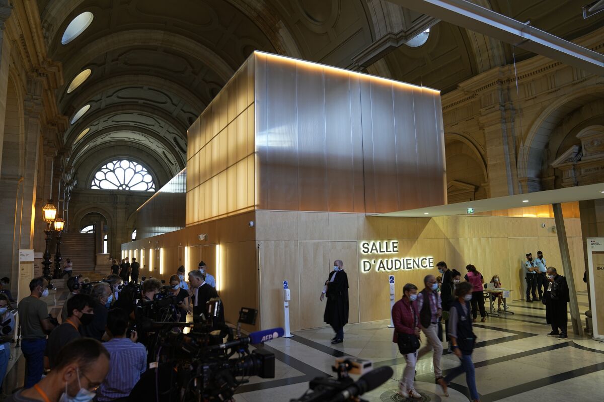 Reporters focus on the special courtroom built for the 2015 attacks trial, Wednesday, Sept. 8, 2021 in Paris. In a custom-built secure complex embedded within a 13th-century courthouse, France opened the trial of 20 men accused in the Islamic State group's 2015 attacks in Paris that left 130 people dead and hundreds injured. Nine gunmen and suicide bombers struck within minutes of each other at France's national soccer stadium, the Bataclan concert hall and Paris restaurants and cafes on Nov. 13, 2015. (AP Photo/Michel Euler)