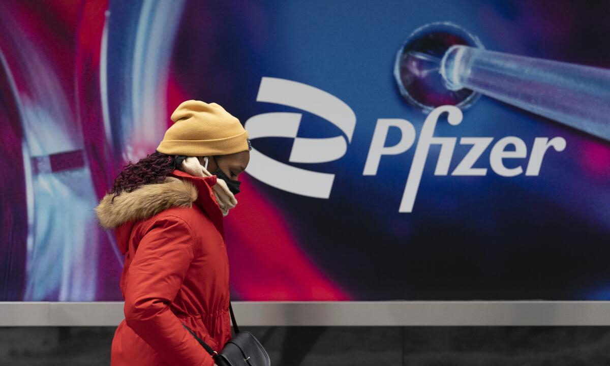 FILE - A woman walks by Pfizer headquarters, Friday, Feb. 5, 2021 in New York. Pfizer reports quarterly financial results Tuesday, Nov. 1, 2022. (AP Photo/Mark Lennihan, File)