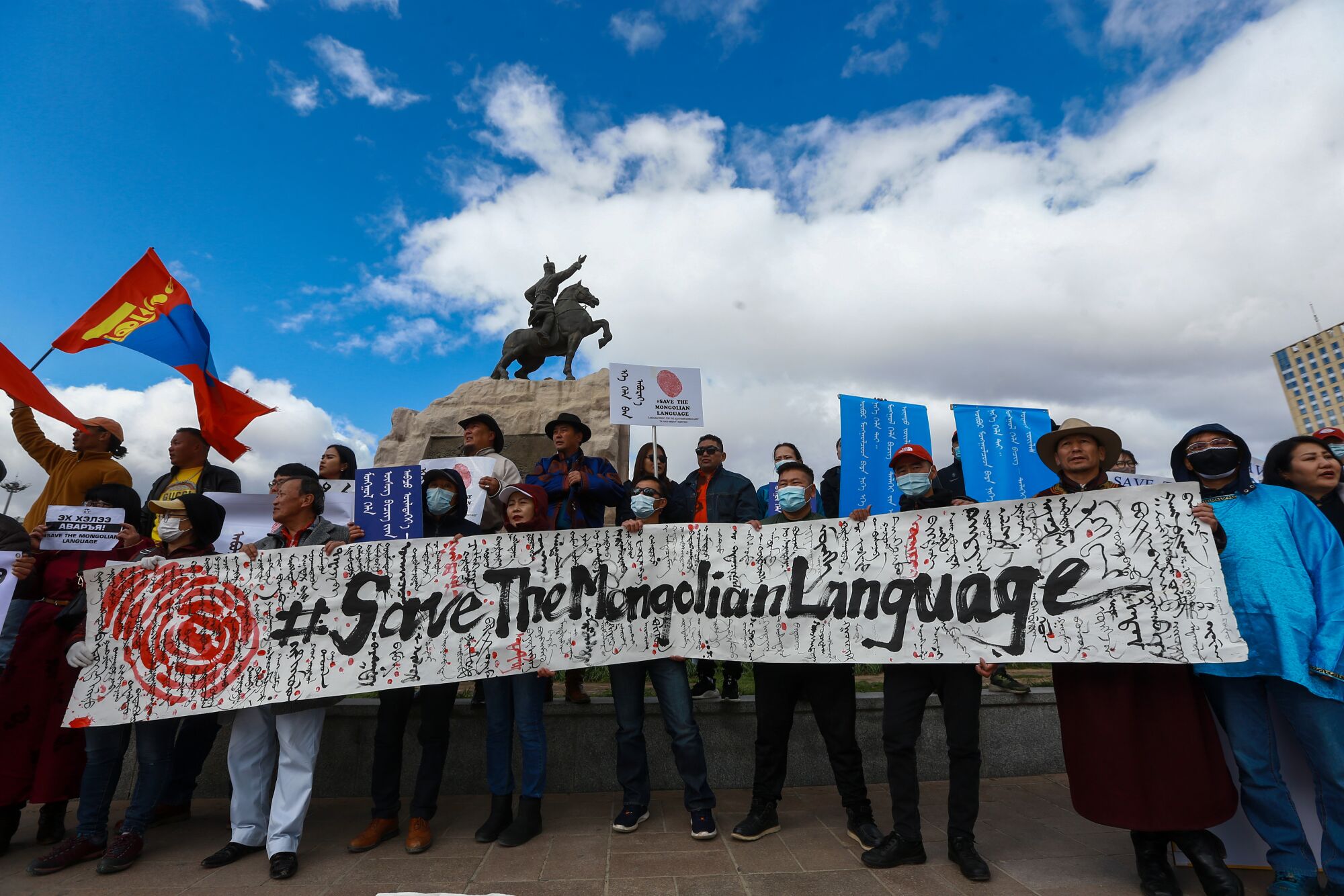 Mongolians march in a line holding a banner reading "Save the Mongolian Language" in English
