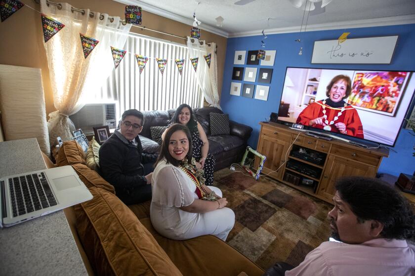ORANGE, CA - MAY 15: Maria Morales, a member of the USC Class of 2020 watches a laptop with Zoom meeting during her virtual graduation via Zoom with her brother Manny Morales, left, mother Pilar Morales and stepdad Victor Ramos, right, on Friday, May 15, 2020 in Orange, CA. (Brian van der Brug / Los Angeles Times)