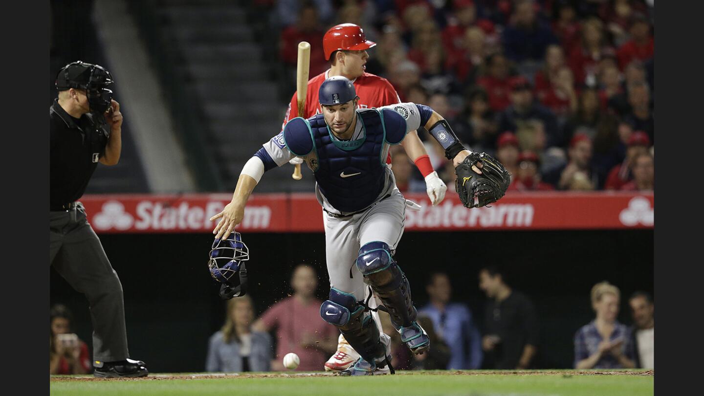 Mariners catcher Mike Zunino runs after a passed ball as batter C.J. Cron signals tothe baserunner during the third inning of a game at Angel Stadium of Anaheim.