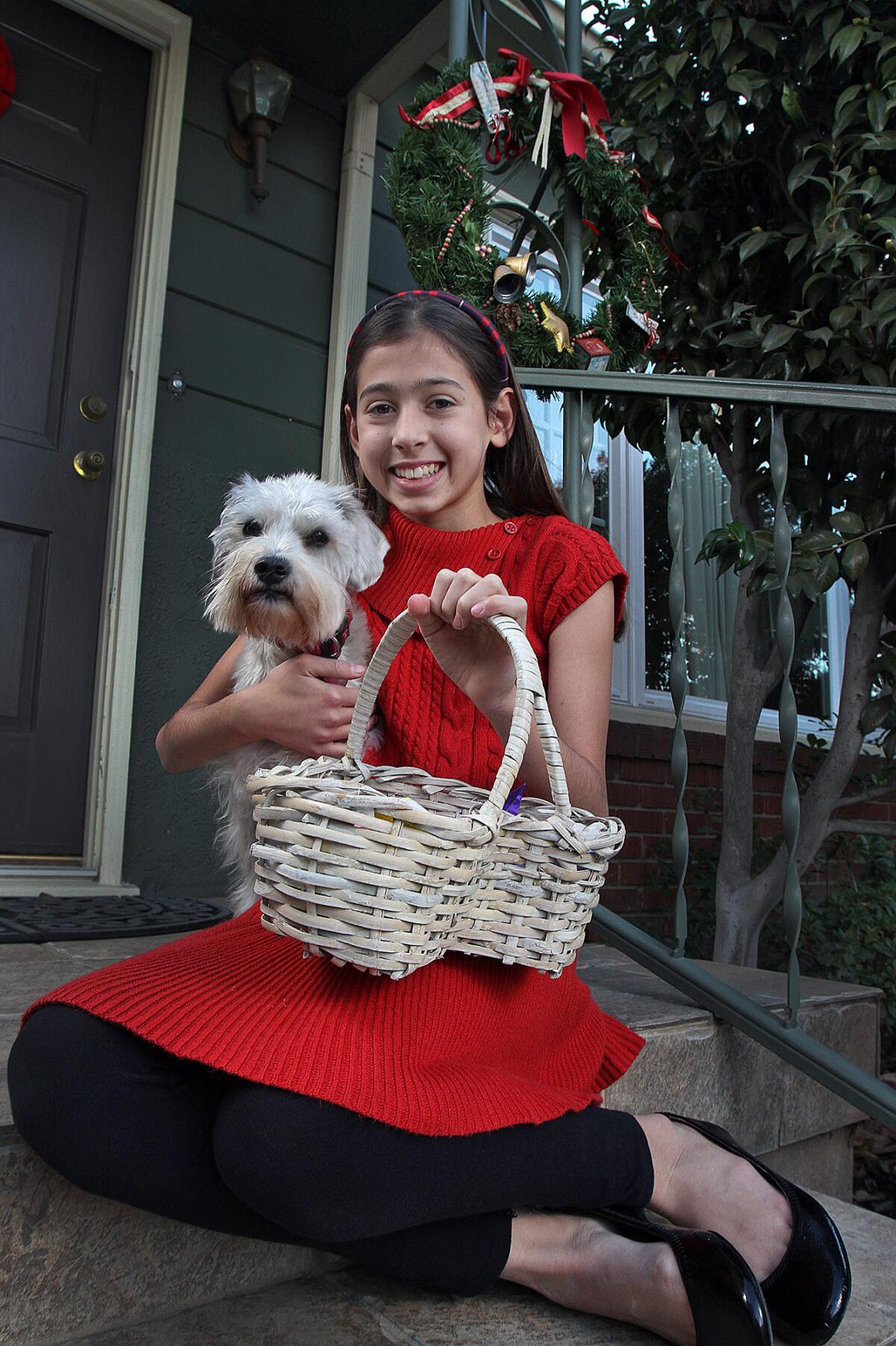 Catherine de Wolff, 10, of Burbank, poses with her dog Nicho and a basket of origami on the front step of her family home.