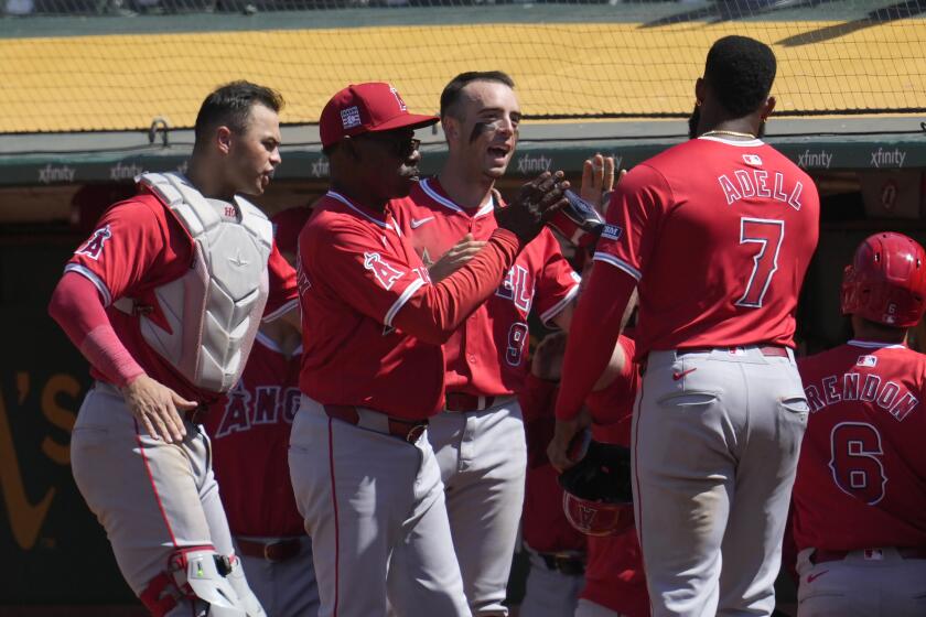 Los Angeles Angels' Jo Adell (7) is congratulated by manager Ron Washington.