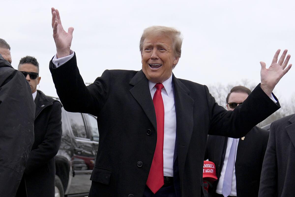 Former President Trump smiling and raising his hands.