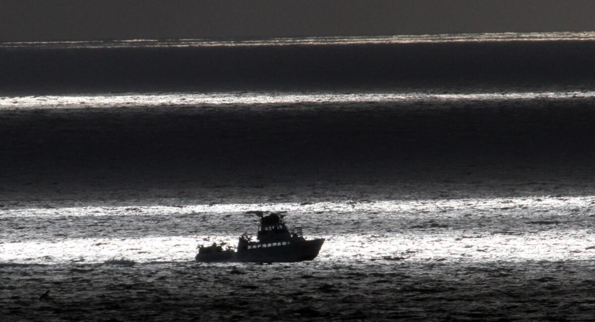 The sun lights a narrow band of the Pacific off San Pedro as a fishing boat chugs past.