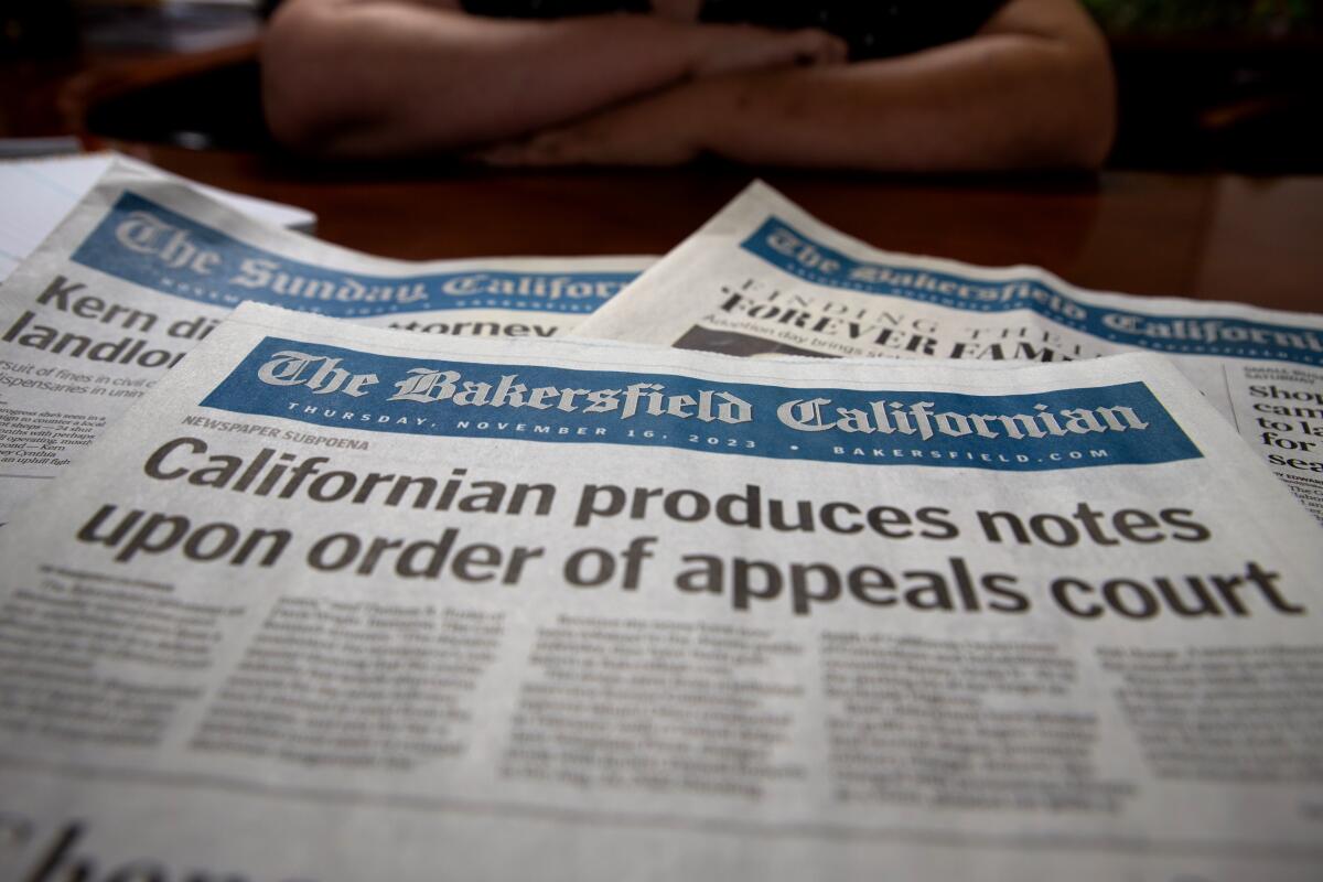 Closeup of newspapers on a desk. A headline reads, "Californian produces notes upon order of appeals court."