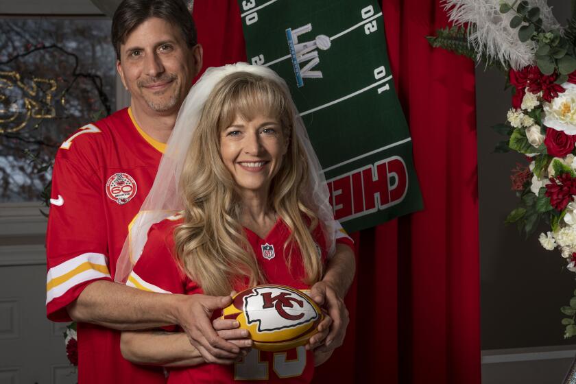 Rob Walkowiak (left) and Nikki Bailey (right) stand in their living room on Friday, Jan. 24, 2020, in Blue Springs, Mo., with some of decorations that will be used in their wedding and reception. The couple are getting married on Super Bowl Sunday. They picked date 0202 2020 because it is a palindrome. At the time, so far in advance, they didn’t realize it was super bowl Sunday. They are RABID chiefs fans and so changed their wedding theme to the Super Bowl. They are doing their first dance in Chiefs jersey.