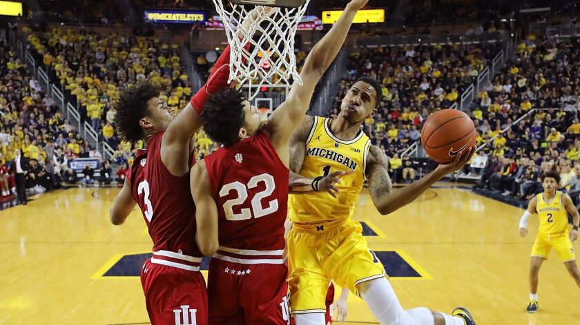 Michigan's Charles Matthews has his layup challenged by Indiana's Clifton Moore (22) and Justin Smith (3) during their game Sunday.