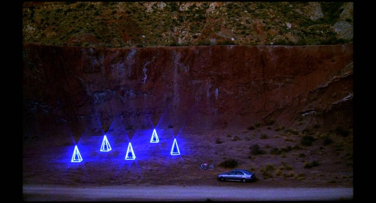 Five glowing pyramids and a car in a ravine