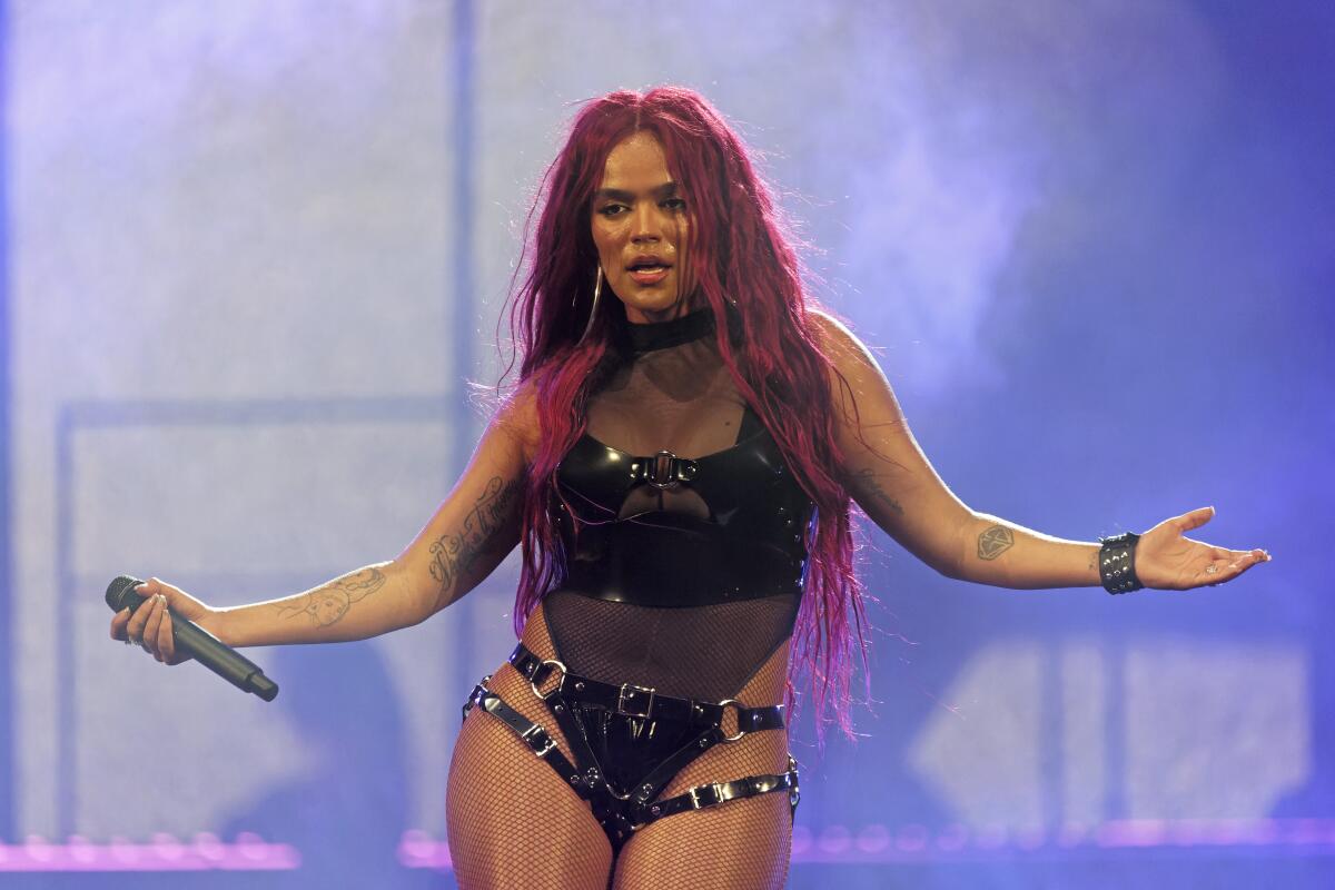 A woman with red hair wearing a black leotard and holding a microphone with her hands at her side