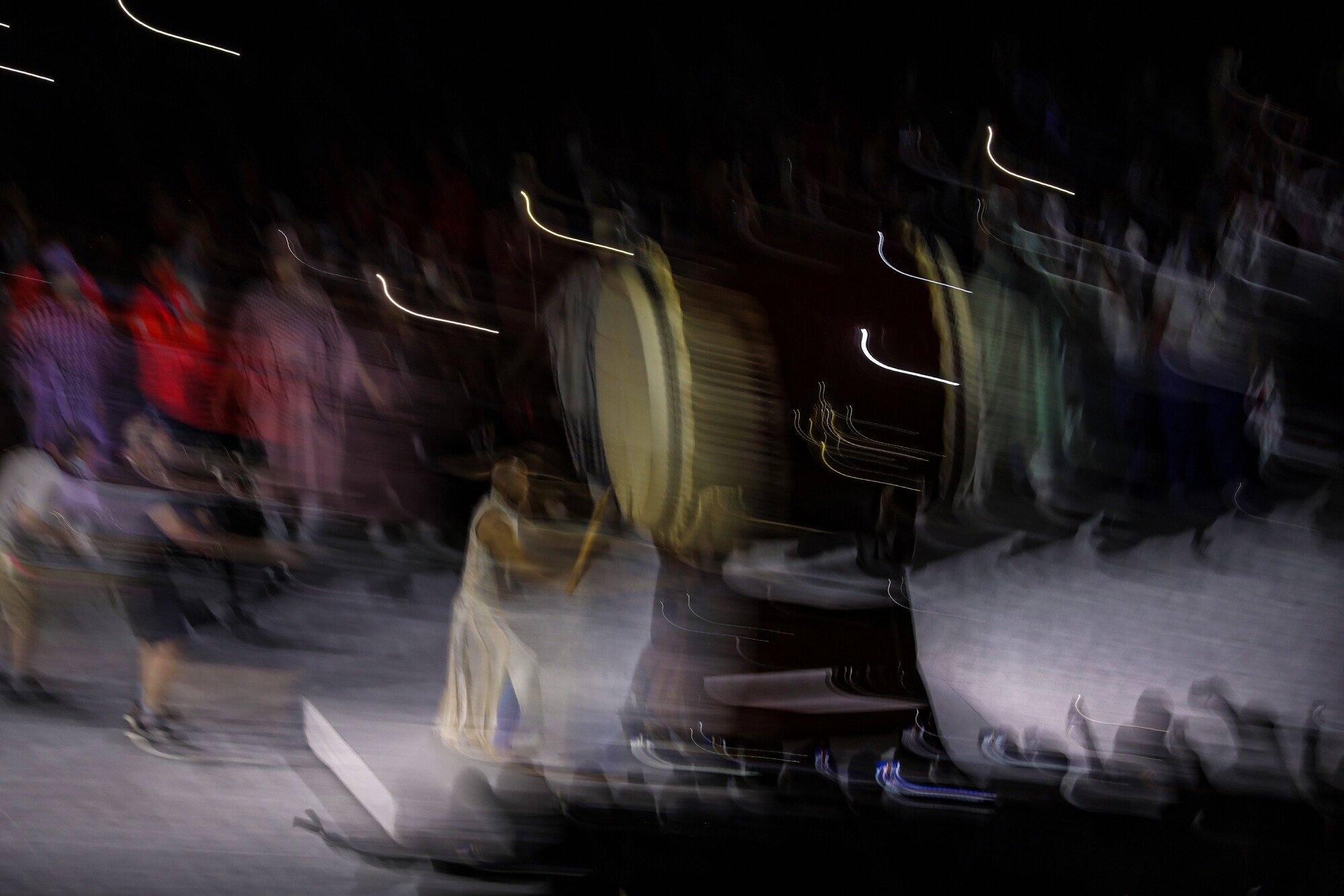 A blurred image shows a person hitting a standing drum.