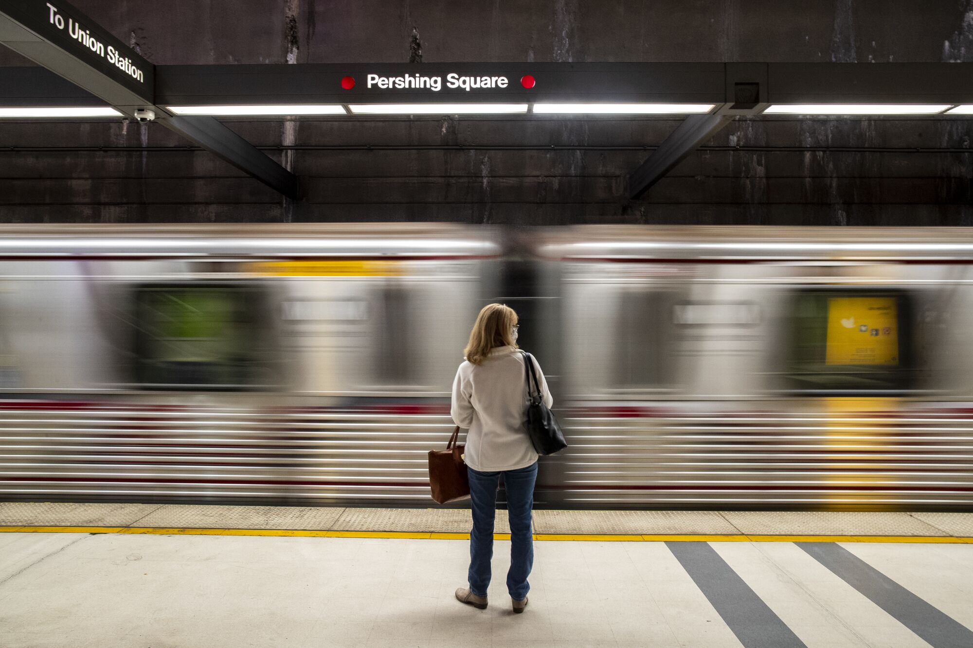 A commuter waits at Pershing Square station for a Metro Red Line train on Nov. 16, 2021.