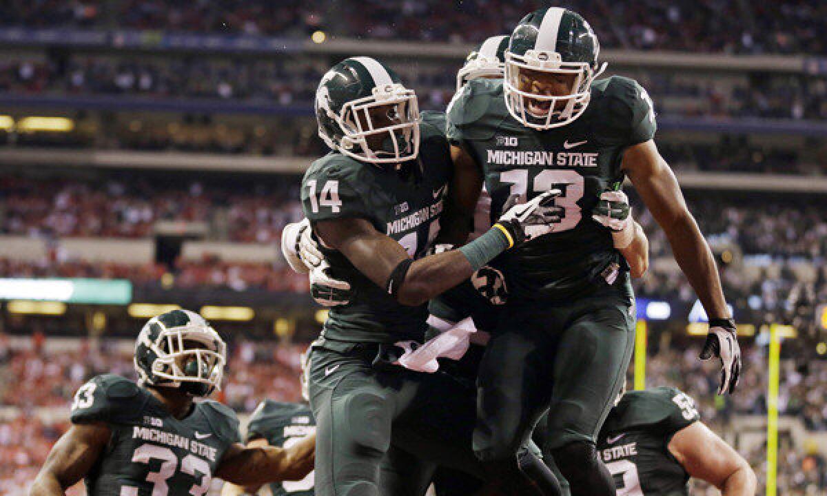 Michigan State's Tony Lippett, top left, celebrates with teammate Bennie Fowler after scoring on a 33-yard touchdown reception during the first half of the Spartans' 34-24 upset win over Ohio State in the Big Ten championship game Saturday.