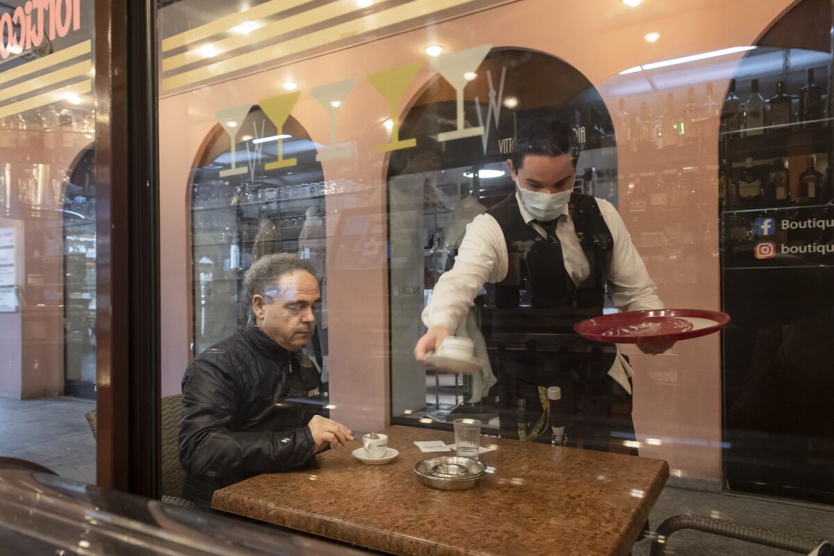 A waiter serves coffee Monday at a restaurant in Switzerland