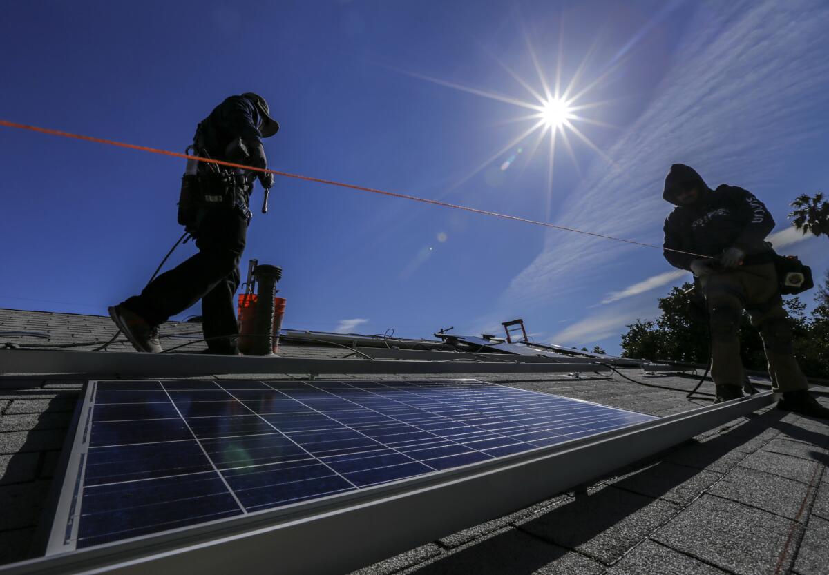 Solar-company workers install panels on a home in Van Nuys in 2016. Today, demand for solar panels has dropped.