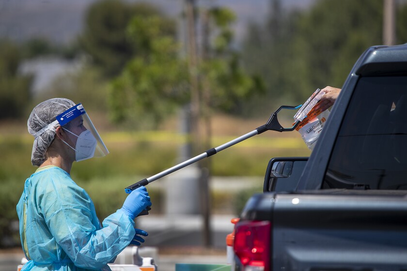 Marissa Arzate retrieves a COVID-19 test from a patient at a drive-through testing site at Orange County Great Park