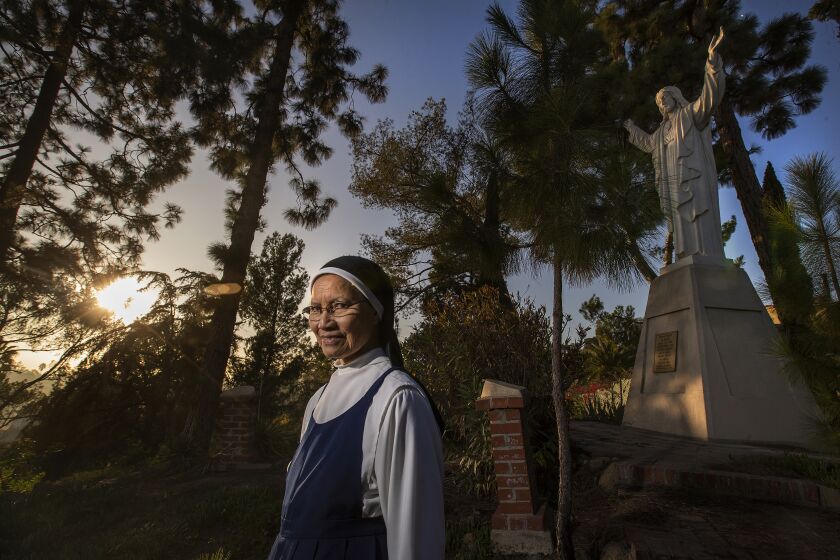 Hollywood, CA - December 01, 2021: Sister Mary John, a cloistered Domincan nun, living at the Monastery of the Angels in Hollywood, is photographed on the grounds next to a statue of Jesus, erected in 1955. Neighborhood organizers and friends of the Monastery of the Angels are gearing up for a battle to save the 90 year old home of the order of cloistered Dominican nuns after hearing that the building will go up for sale in 2022. (Mel Melcon / Los Angeles Times)
