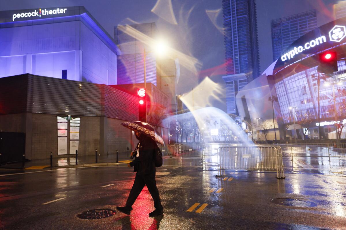 A person walks under an umbrella at L.A. Live.