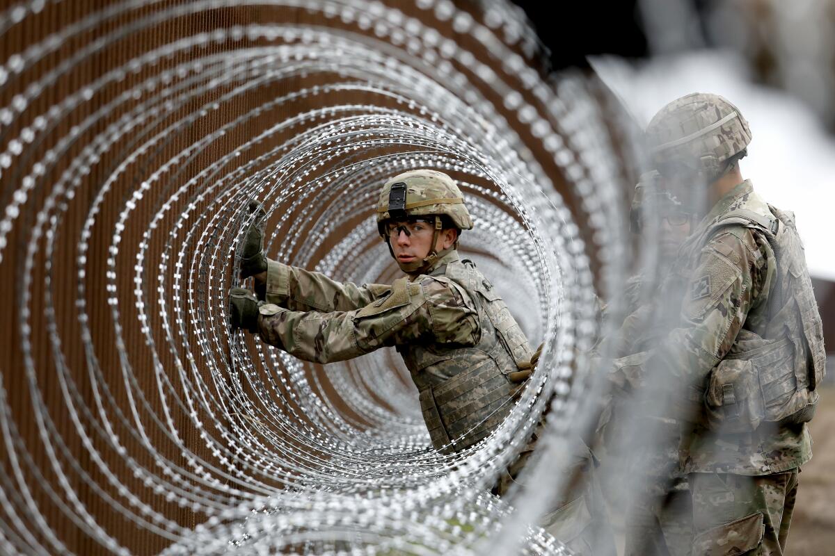 Alexander Gomez and U.S. Army troops install coils of wire along the border in Brownsville, Texas, on Nov. 13, 2018.
