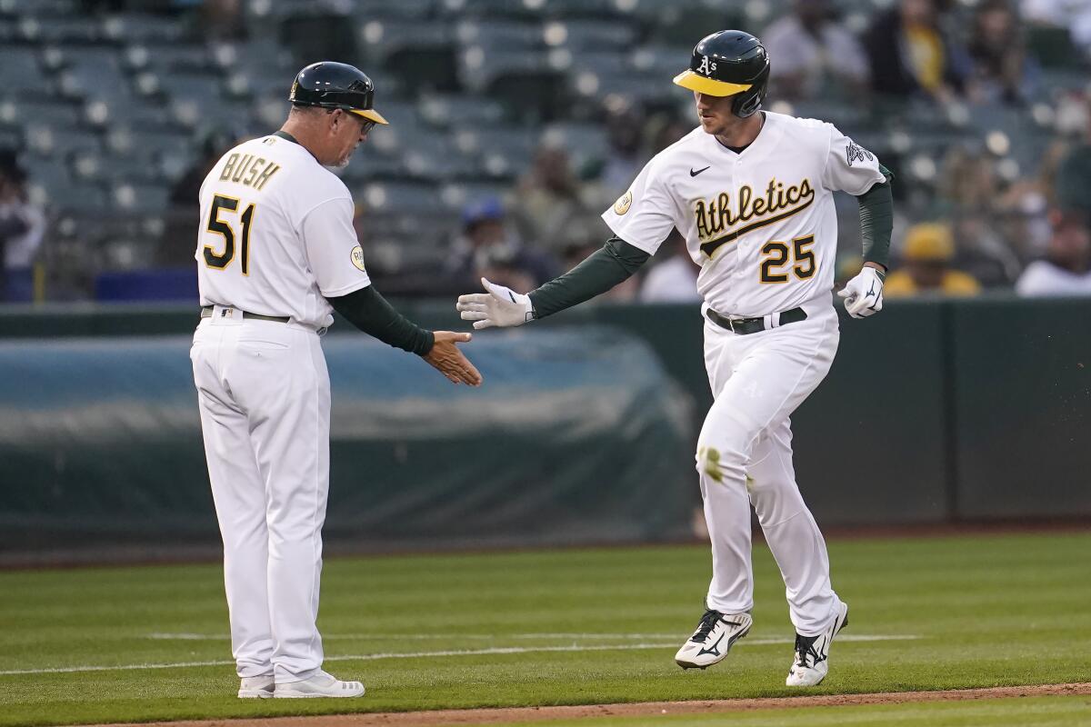Oakland Athletics' Stephen Piscotty (25) is congratulated by third base coach Darren Bush (51) after hitting a home run during the fifth inning of the team's baseball game against the Toronto Blue Jays in Oakland, Calif., Tuesday, July 5, 2022. (AP Photo/Jeff Chiu)